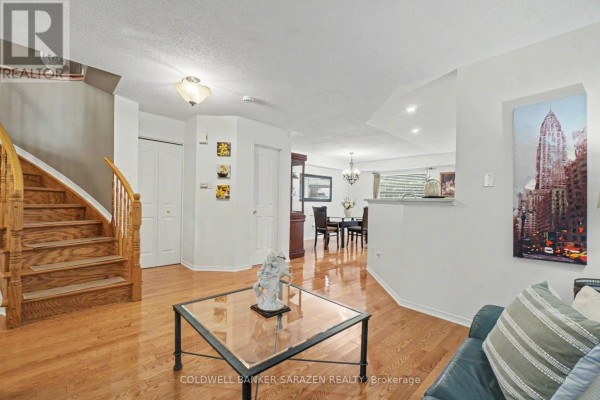 Living and dining area with hardwood floors, staircase, and a view into the dining space. - 2020 Breezewood Street, Ottawa