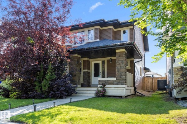 Close-up of the covered front porch with stone pillars, brown siding, and a white door. - 2020 Glenridding Gate Ga Sw, Edmonton