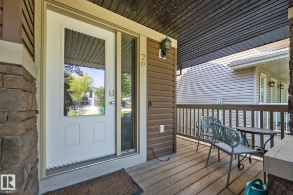 Backyard view of a two-story brown house with a wooden deck, a planter box, and a grass lawn. - 2020 Glenridding Gate Ga Sw, Edmonton