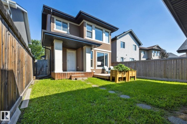 Wooden deck in the backyard with two blue chairs and a view of a garage and wooden fence. - 2020 Glenridding Gate Ga Sw, Edmonton