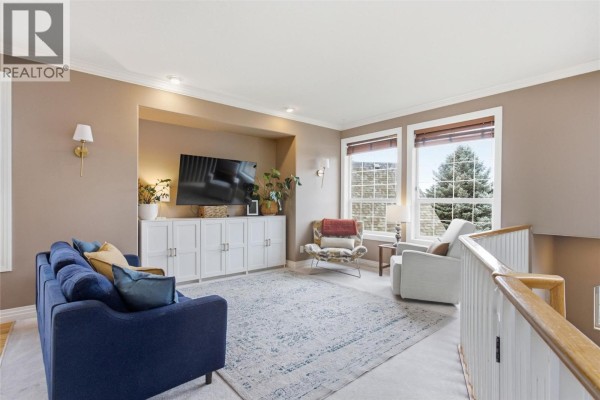 Cozy sitting area with a blue sofa, armchair, and built-in entertainment unit. - 2025 Panorama Court, Kamloops