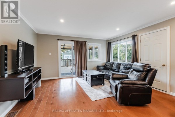 Living room with dark leather sofa, recliner, coffee table, entertainment unit, and hardwood floors. - 20251 Kenyon Conc Rd 1 Concession, North Glengarry