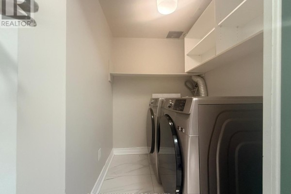 Laundry room with stacked silver washer and dryer and white shelving above. - 2028 - 75 Bamburgh Circle, Toronto