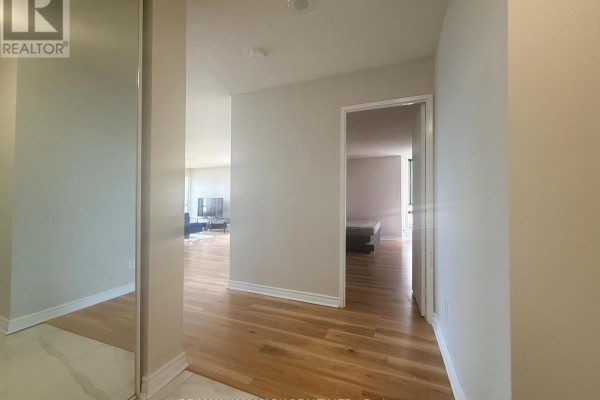 Hallway inside apartment with hardwood floors, leading to living room and bedroom. - 2028 - 75 Bamburgh Circle, Toronto