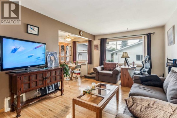 Living room featuring a sofa, armchair, coffee table, television, and a view into the dining area. - 2029 Mountview Crescent Ne, Calgary