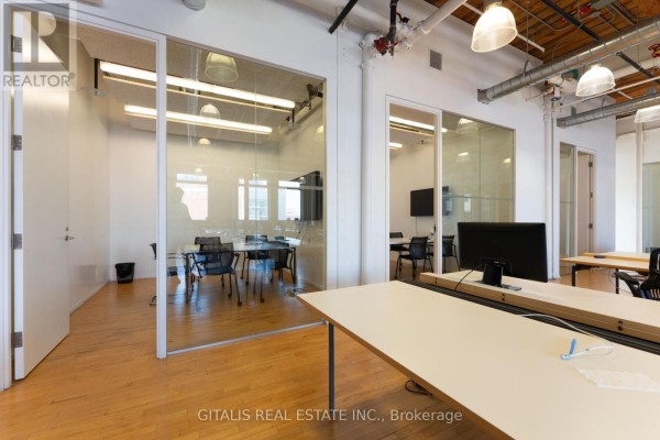 Gym area with treadmills and exercise bikes next to a large window overlooking a parking lot. - 202a - 219 Dufferin Street, Toronto