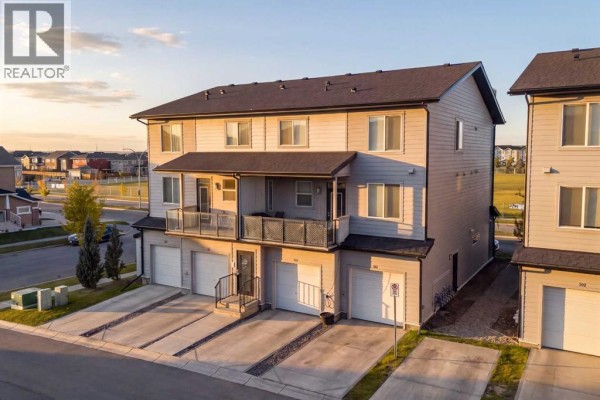 Exterior view of attached townhouses with three garage doors on the lower level. - 203, 315 Redstone Walk Ne, Calgary