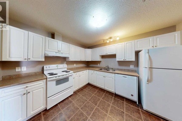 Dining area with a round table, grey chairs, and a white sideboard. - 203, 9508 99 Street, Lac La Biche