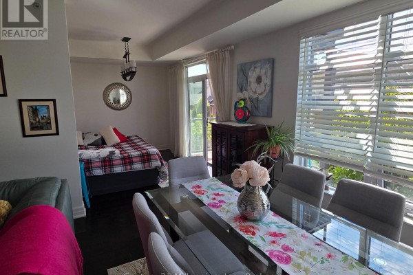 Dining area with a glass table, grey chairs, and a bed with red plaid bedding in background. - 203 - 1 Shipyard Lane, Collingwood