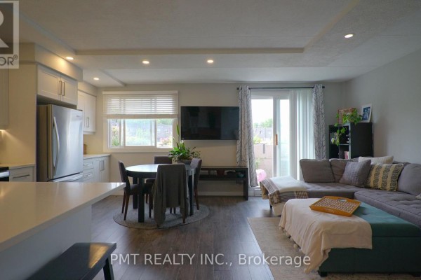 Open concept living and dining area with a sectional sofa, TV, and dining table. - 203 - 10 Cooper Street, Cambridge