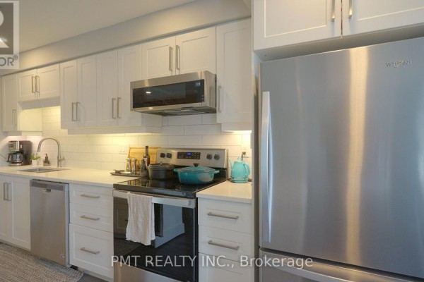 Kitchen detail showing white cabinets, stainless steel stove, refrigerator, and island. - 203 - 10 Cooper Street, Cambridge