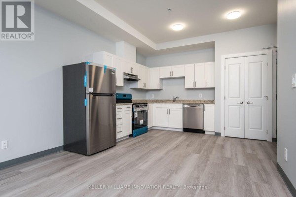 Kitchen with white cabinets, granite countertops, stainless steel appliances, and light wood floors. - 203 - 10 Queen Street, St  Thomas