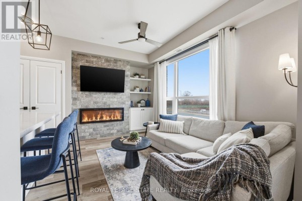 Living room with fireplace, television, sectional sofa, coffee table, and large window. - 203 - 120 Springvalley Crescent, Hamilton