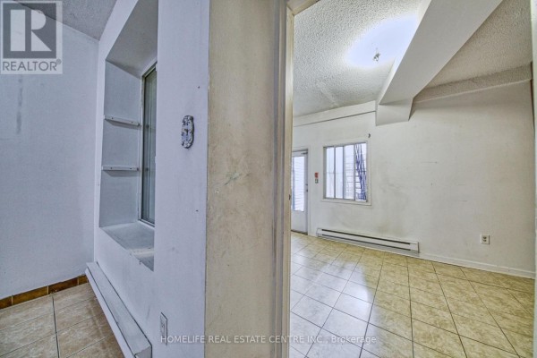 A hallway with a built-in shelf niche and a doorway leading into another room. - 203 - 223 Jameson Avenue, Toronto