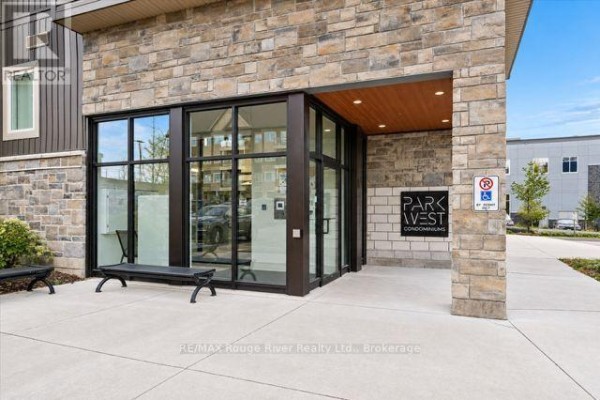 Close-up of the main entrance of Park West Condominiums with stone facade and glass doors. - 203 - 340 Florence Drive, Peterborough