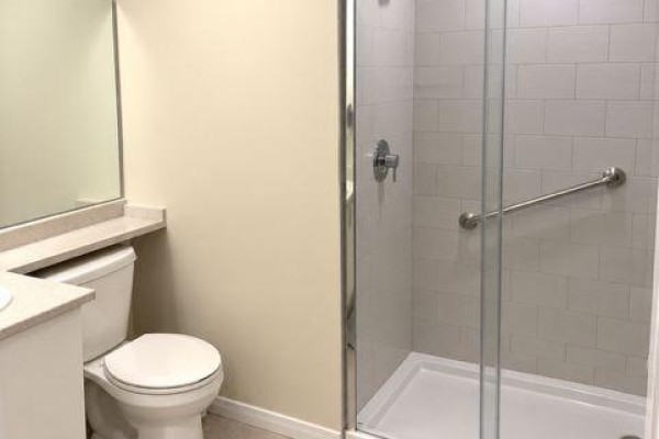 Bathroom featuring a toilet, vanity, and a glass-enclosed walk-in shower with subway tiles. - 203 - 340 Florence Drive, Peterborough