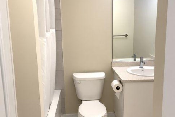 Bathroom with a bathtub, toilet, vanity, and sink, with a large mirror above the vanity. - 203 - 340 Florence Drive, Peterborough