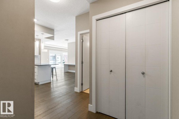 Hallway in an apartment with a white door and double closet doors. - #203 10006 83 Av Nw, Edmonton