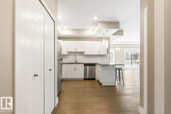 View from an apartment hallway into the kitchen and living area. - #203 10006 83 Av Nw, Edmonton