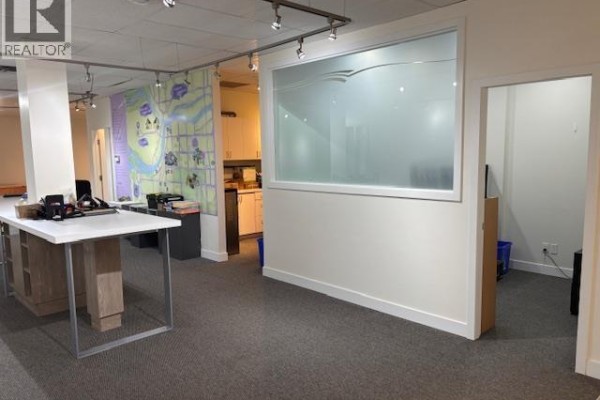 Office with a large white desk, carpeted floor, and a frosted glass divider. - 203-204 8580 Cambie Road, Richmond