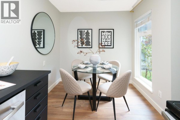 Living room with light-colored walls, a sofa, coffee table, and large sliding glass doors. - 203 2240 Wall Street, Vancouver