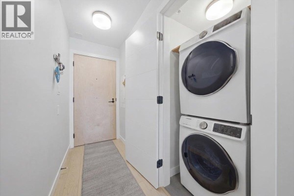 Interior hallway with stacked white washer and dryer unit. - 203 2508 Fraser Street, Vancouver