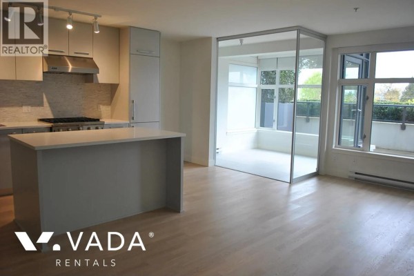 Kitchen with stainless steel appliances, island, and view of a sunroom. - 203 4355 W 10th Avenue, Vancouver