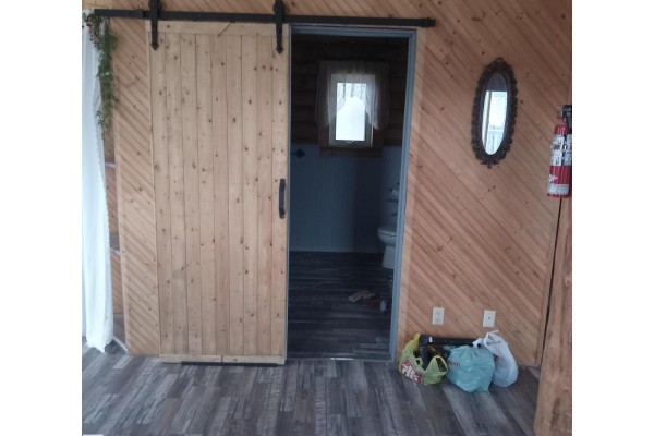 Sliding barn door leading to a bathroom area with wooden paneling. - #203 60331 Range Road 124, Rural Smoky Lake County
