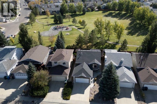 Aerial view of residential homes facing a green park with a playground. - 203 Blackfoot Circle W, Lethbridge