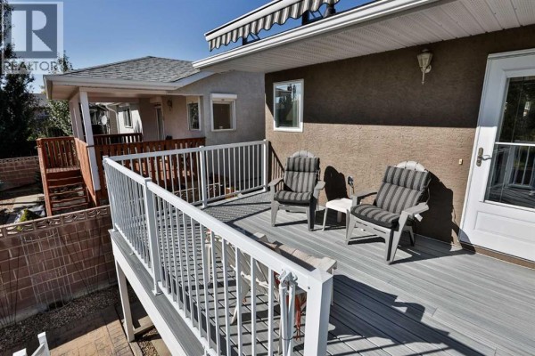 Deck with grey composite flooring, white railings, and outdoor chairs. - 203 Blackfoot Circle W, Lethbridge