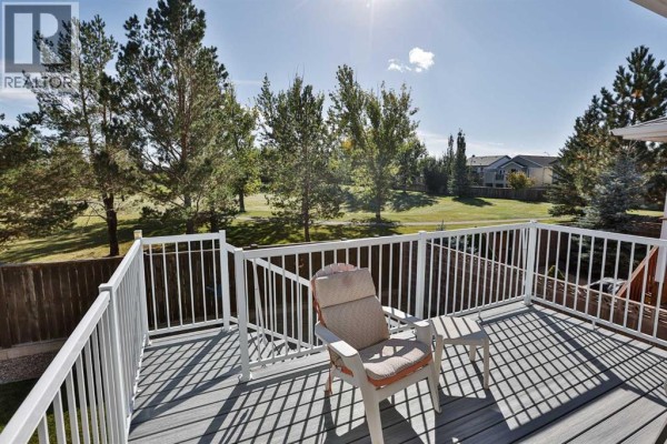 Deck view overlooking a grassy park area with trees and houses. - 203 Blackfoot Circle W, Lethbridge