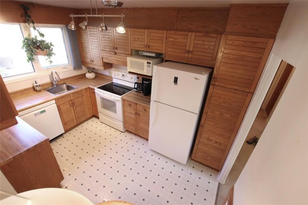 Oak kitchen cabinets and butcher block counters with white appliances and a checkered floor. - 203 Harold Avenue, Winnipeg