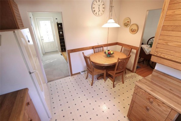 Round oak dining table and chairs in a breakfast nook with wainscoting and a window. - 203 Harold Avenue, Winnipeg