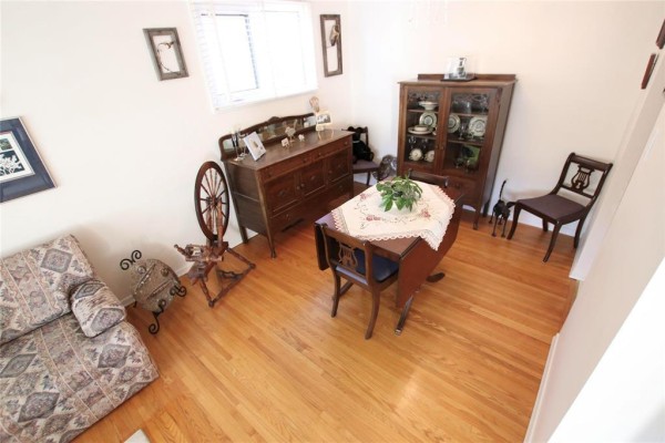 Dining room area with a wooden hutch, drop-leaf table, chairs, and hardwood floors. - 203 Harold Avenue, Winnipeg
