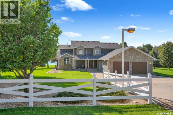 Front view of a two-story house with stone and dark siding, a covered porch, and a white fence in the yard. - 203 North Shore Drive, North Grove