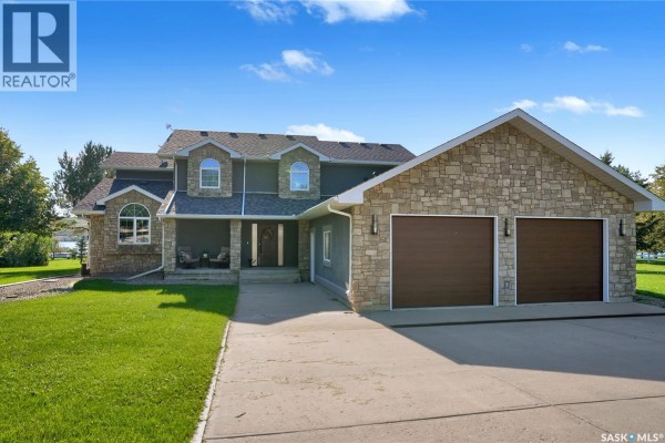 Frontal view of a large, multi-story house with stone and siding exterior, a covered entry, and double garage doors. - 203 North Shore Drive, North Grove