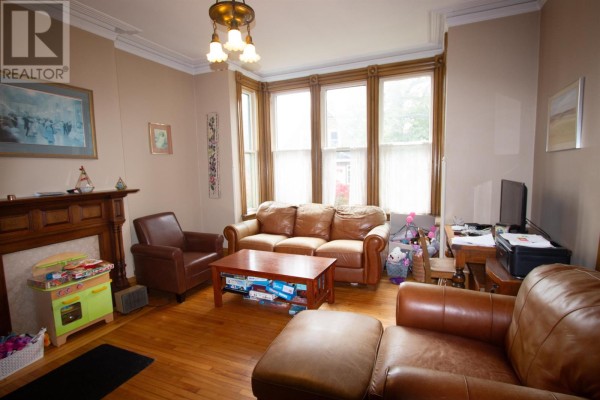 Living room with leather sofas, a wooden coffee table, and a bay window. - 203 Notre Dame Street, Summerside