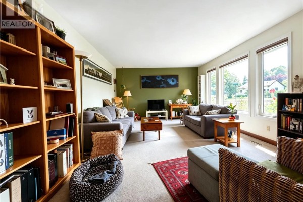 Living room with light green walls, two sofas, wood bookshelves, and large windows. - 203 Pottery Street, Eastend