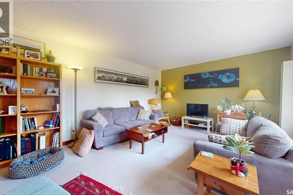 Living room with light green accent wall, two sofas, wood bookshelves, and television. - 203 Pottery Street, Eastend