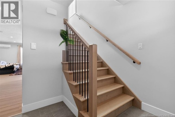 Close-up of the staircase with wooden steps and black metal railing. - 203 Teaberry Avenue, Moncton