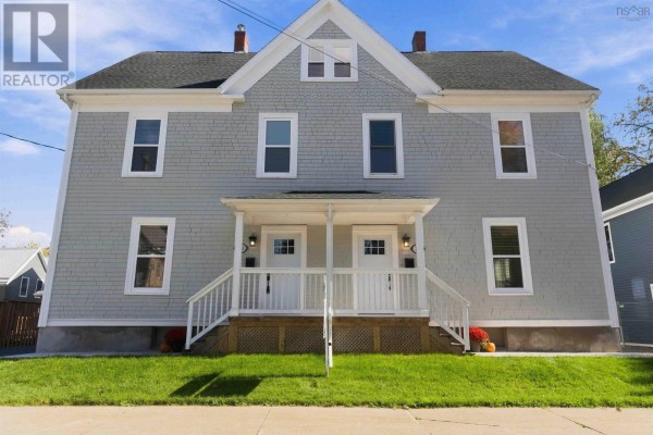 Low-angle side view of a light blue duplex with a grassy lawn and sidewalk. - 203/205 Gray Street, Windsor