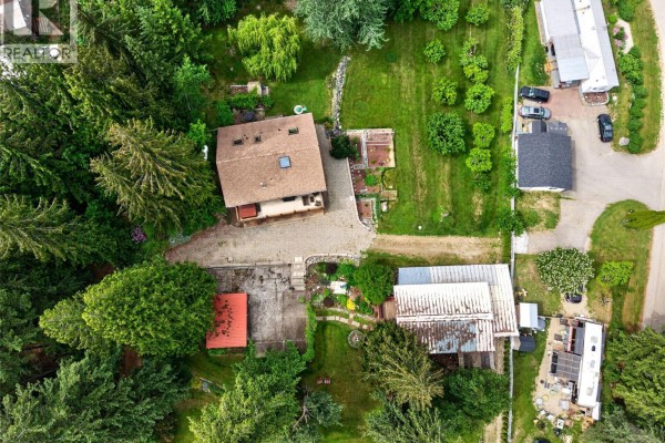 Overhead aerial view of a red-roofed house with a large gravel driveway and surrounding greenery. - 2030 Solsqua-sicamous Road, Sicamous