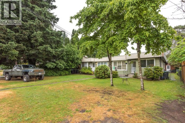 Wide exterior shot of the duplex with a truck parked on the grass and mature trees. - 2031 Manning Avenue, Port Coquitlam