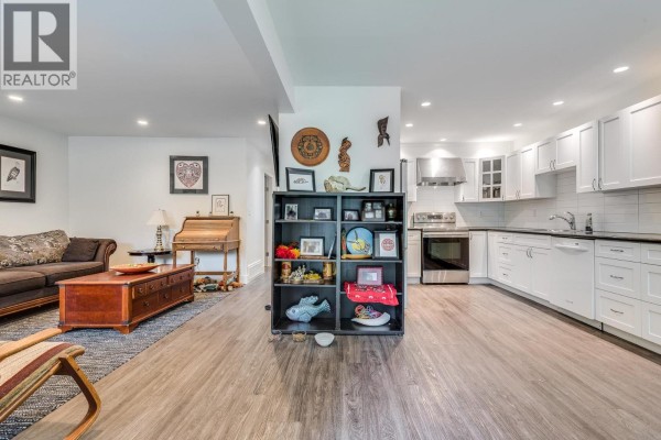 Open concept living area and kitchen with white cabinets, stainless steel appliances, and dark laminate flooring. - 2031 Manning Avenue, Port Coquitlam