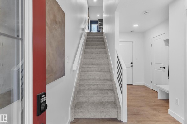 Staircase with grey carpet and black railing leading to upper floor. - 2032 Marquis Wy Ne, Edmonton