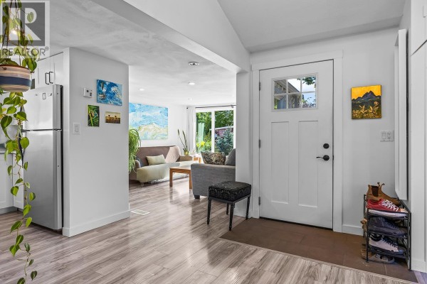 Entrance hallway with white door, view of living room and kitchen with stainless steel appliances. - 2035 Boucherie Road Unit# 36, West Kelowna