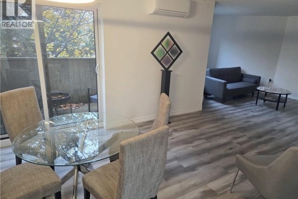 Dining area with glass table and chairs, adjacent to a living area with sofa. - 2035 South Millway End Unit# 62, Mississauga