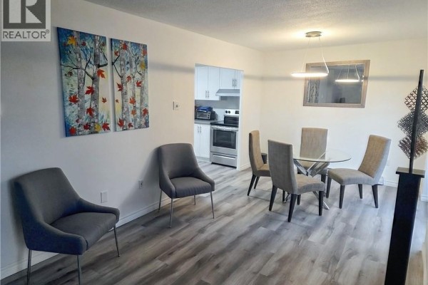 Living and dining area with gray chairs, glass table, and view of the kitchen. - 2035 South Millway End Unit# 62, Mississauga