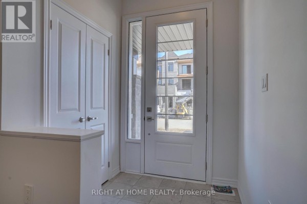 Interior view of a front entryway with a glass-paneled door showing the exterior under construction. - 2038 Cameron Lott Crescent, Oshawa