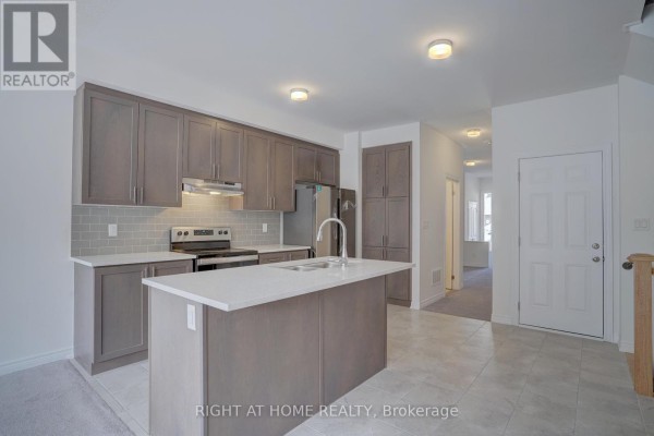 Contemporary kitchen with grey cabinetry, white quartz countertops, island, stainless steel appliances, and tile flooring. - 2038 Cameron Lott Crescent, Oshawa